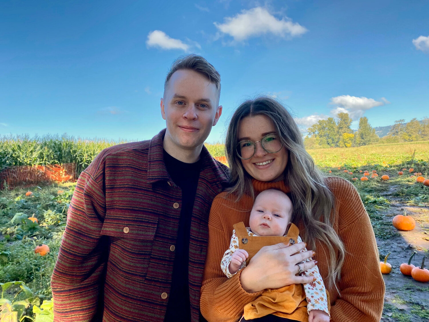 Danny and Robyn pose for a photo with Juniper at a pumpkin patch.